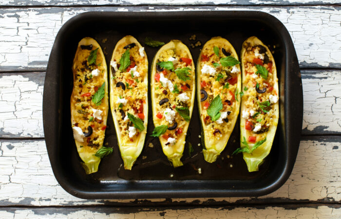 Eggplants stuffed with couscous vegetables, soft cheese and olives on black baking sheet Aubergines